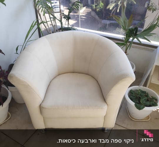 כורסה לבנה על רצפת אריחים ליד צמחים בעציצים